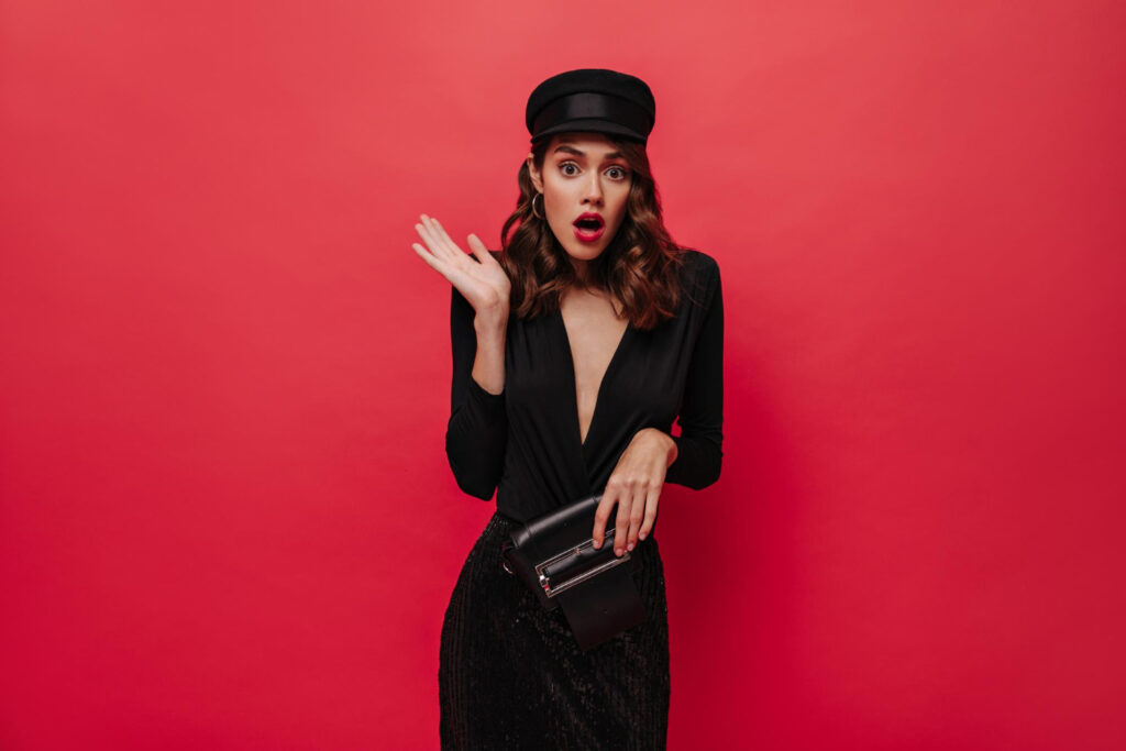 Shocked woman rises arms Elegant lady in black cap and festive dress
