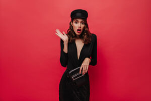 Shocked woman rises arms Elegant lady in black cap and festive dress