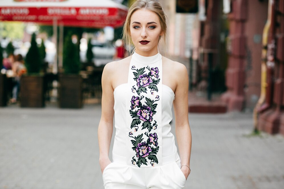 Young woman in a white floral jumpsuit walking on a city street.