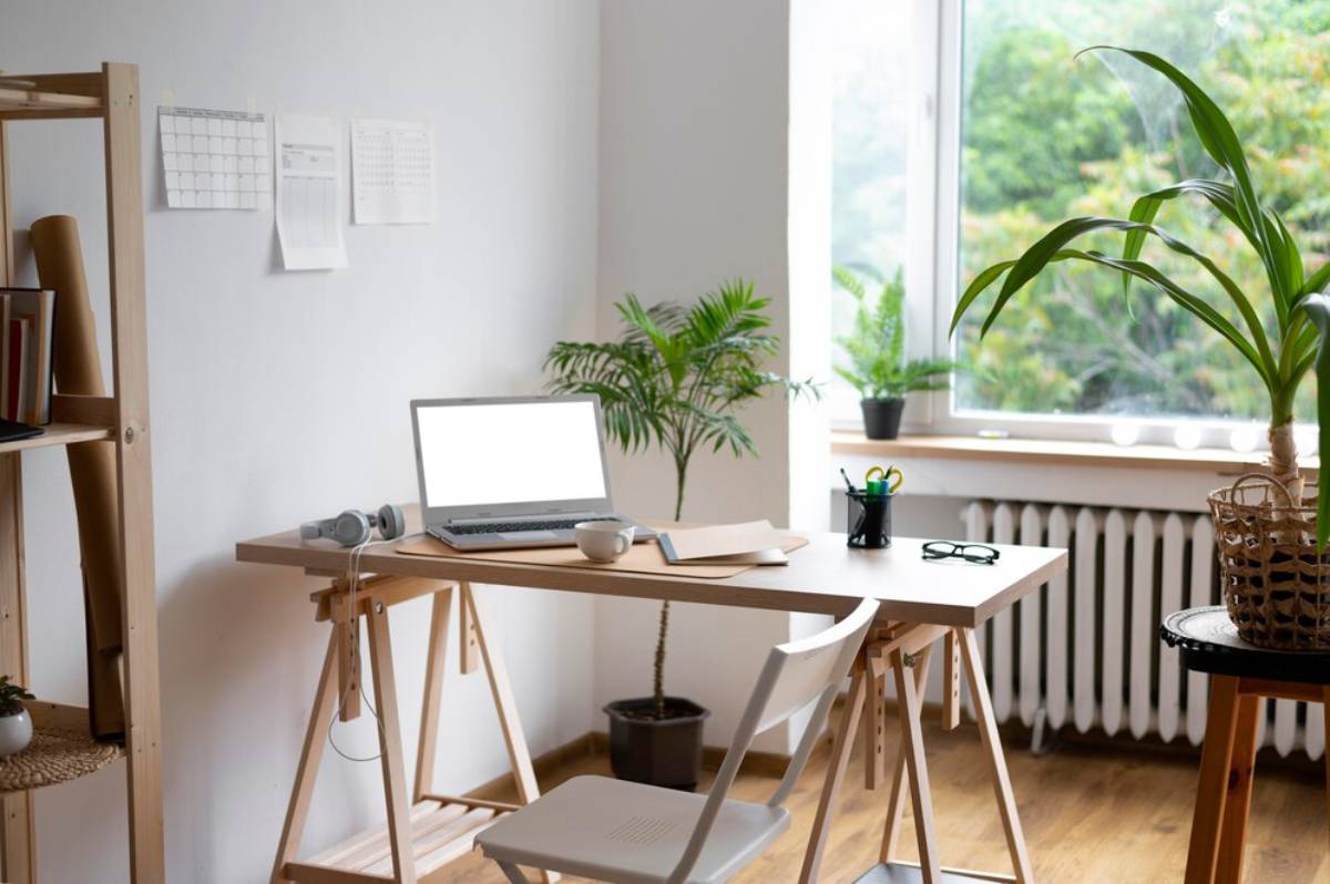Bright home office with a laptop on a desk, plants by a window, and minimal decor.