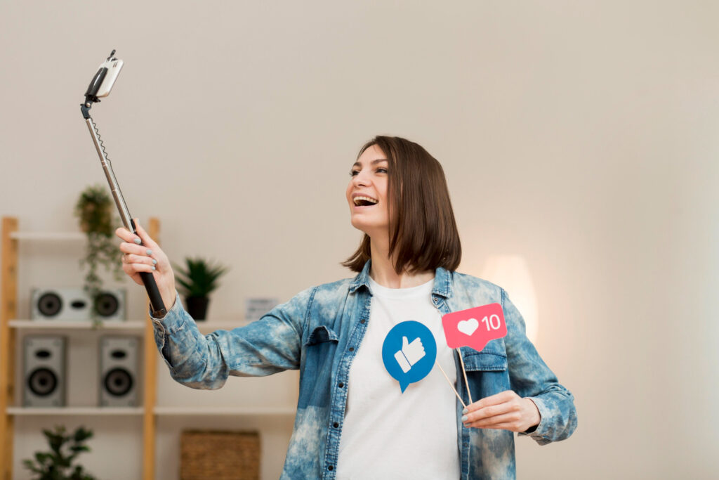 A person in a denim jacket holds a selfie stick while displaying social media