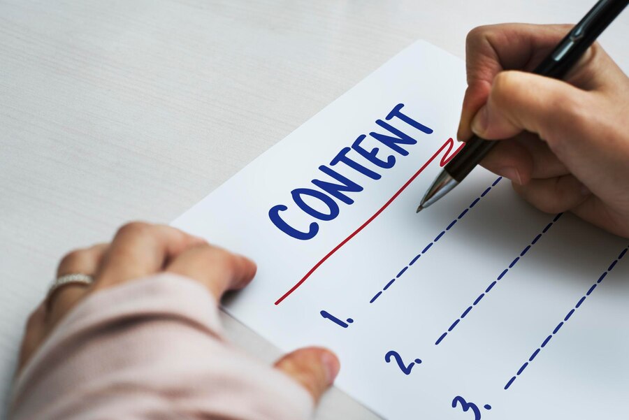 Person writing a content list on white paper, highlighting CONTENT with a black pen.