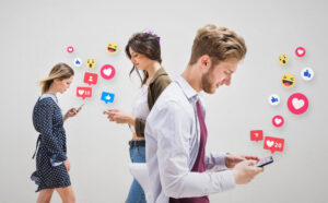 Three people engrossed in smartphones with floating social media icons above their heads, against a white background.