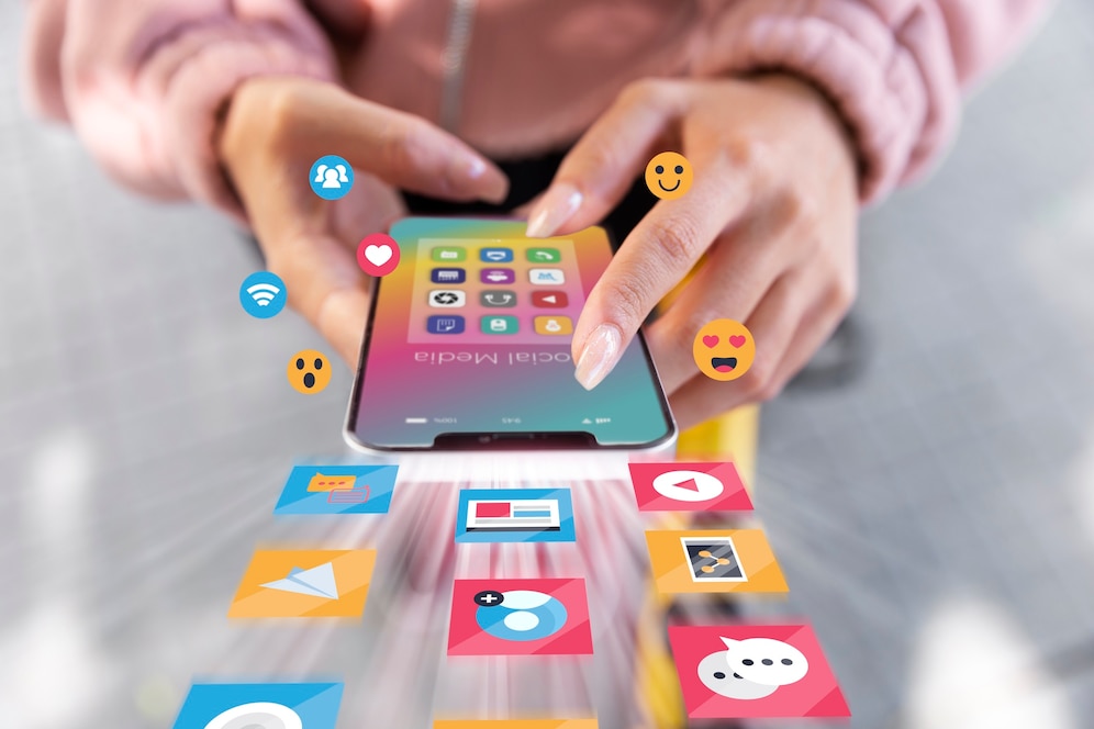 Close-up of hands using a smartphone, with floating social media and communication icons.