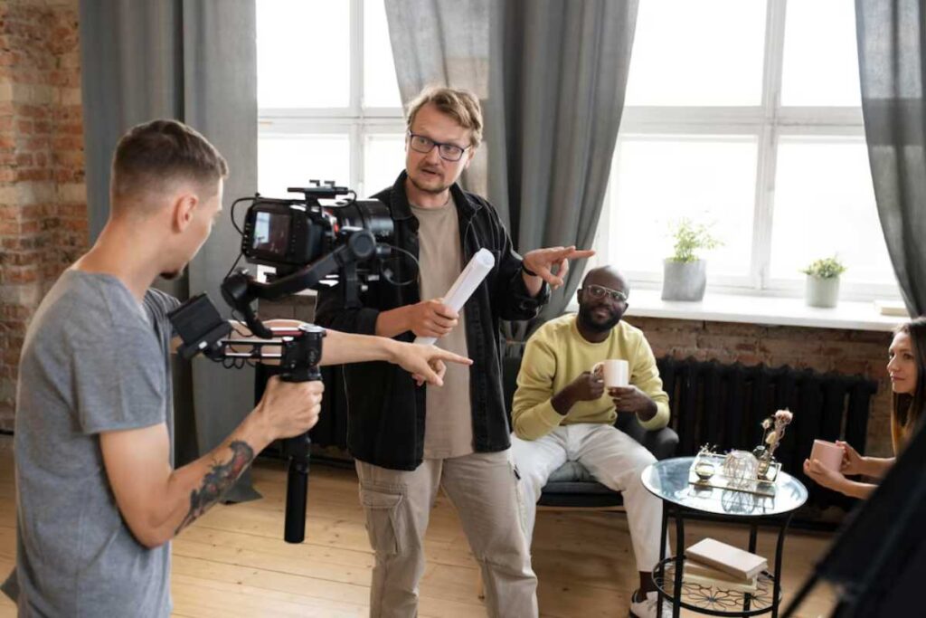A film crew recording a scene in a loft, with a director giving instructions to actors and cameraman.