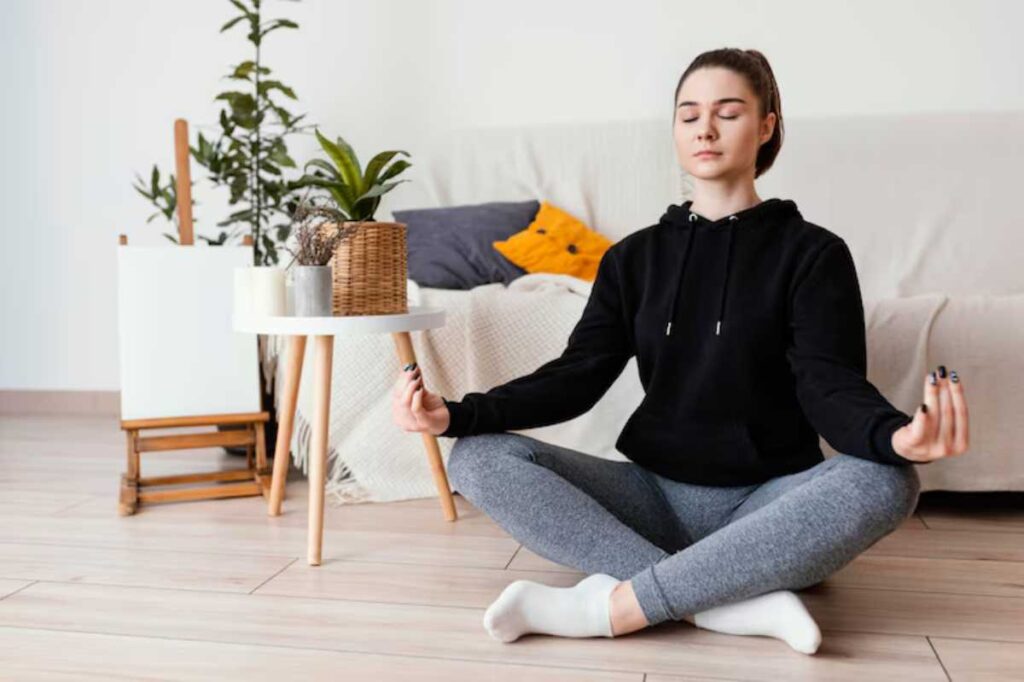 Young woman meditating on the floor in a cosy home environment.