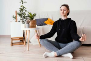 Young woman meditating on the floor in a cosy home environment.