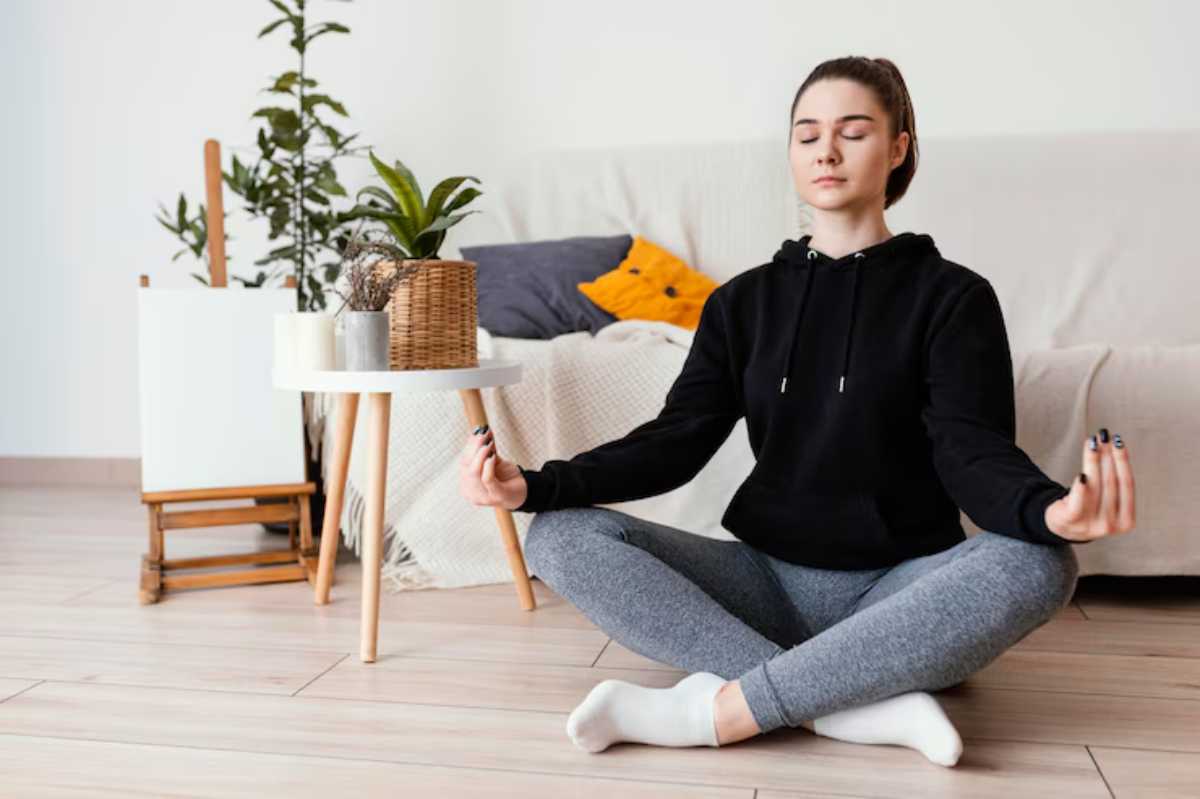 Young woman meditating on the floor in a cosy home environment.