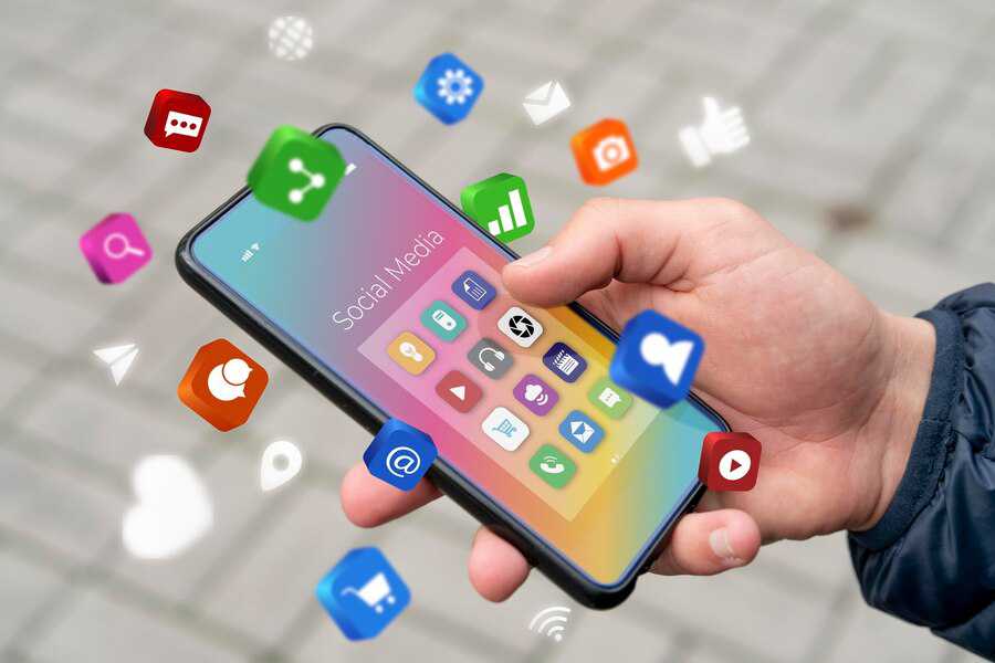 Hand holding a smartphone with floating social media icons above the screen.