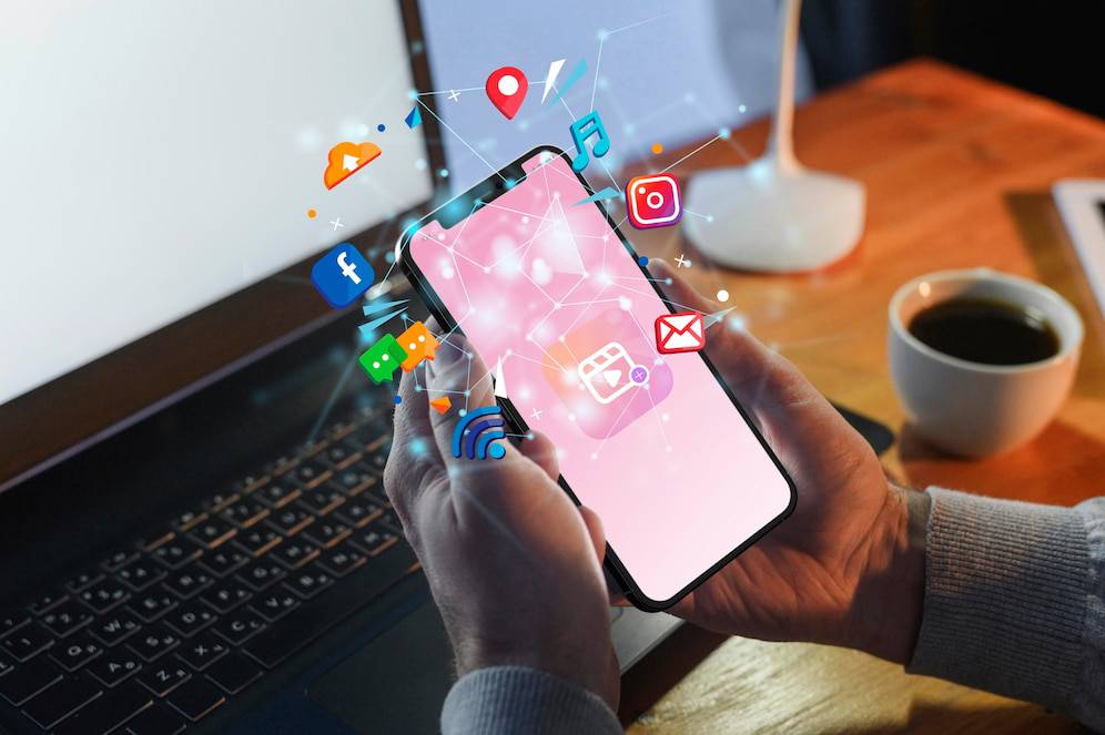 A person holding a smartphone with social media icons floating above